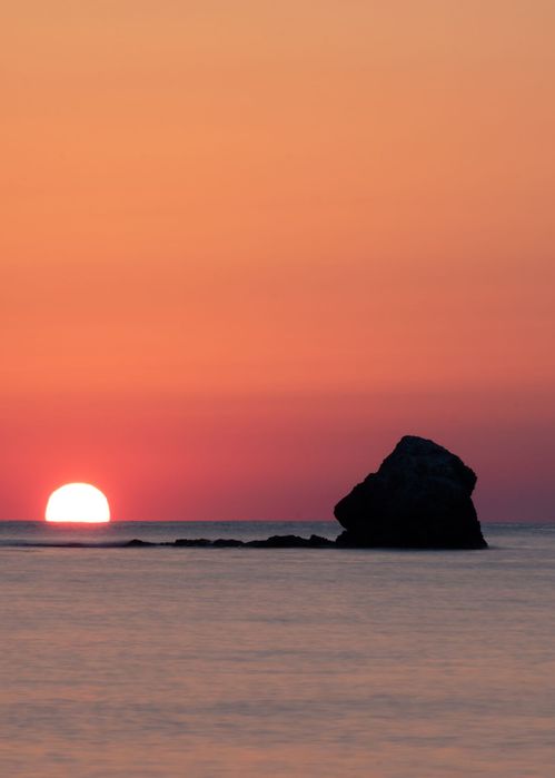 Снимка на изгряващото слънце над Черно море и скала приличаща на глава